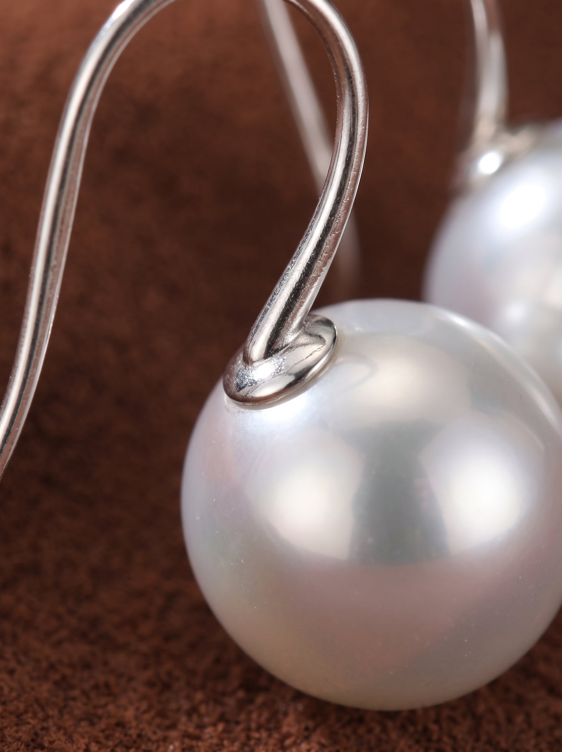 Close-up of elegant Alight Akoya Pearl Hoop Earrings featuring lustrous, perfectly round 9mm black pearls dangling from silver hoops on a silver hoop. @pearl