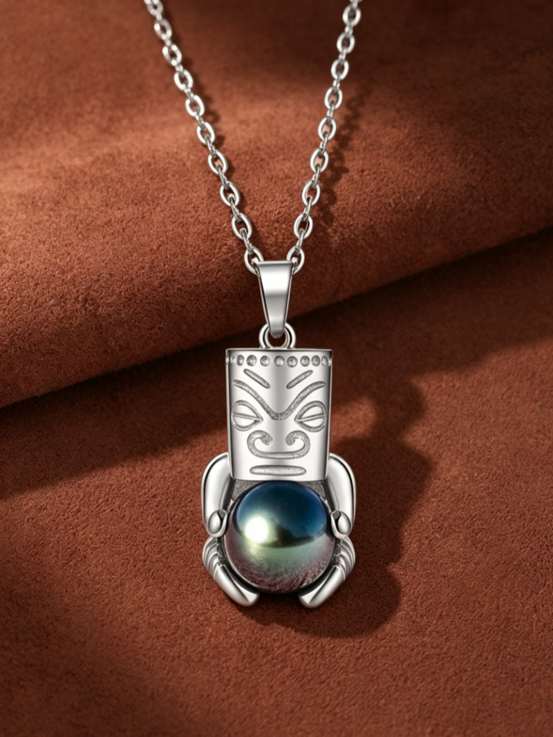 Close-up of the Ancestral Tahitian Pearl Tiki Drop Necklace, showcasing a detailed silver Tiki pendant cradling a lustrous, iridescent black Tahitian pearl on a delicate silver chain.