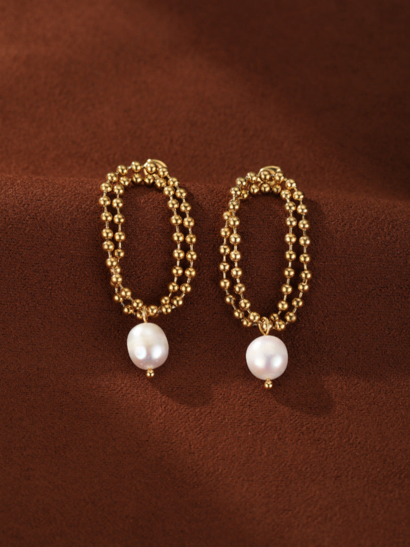 Gold tone double strand beaded oval drop earrings featuring a single 8mm white freshwater pearl dangling from each.