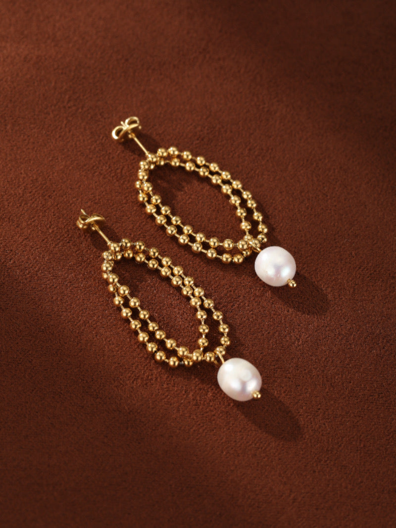 A pair of gold-tone double-strand beaded oval drop earrings, each featuring a lustrous white freshwater pearl.