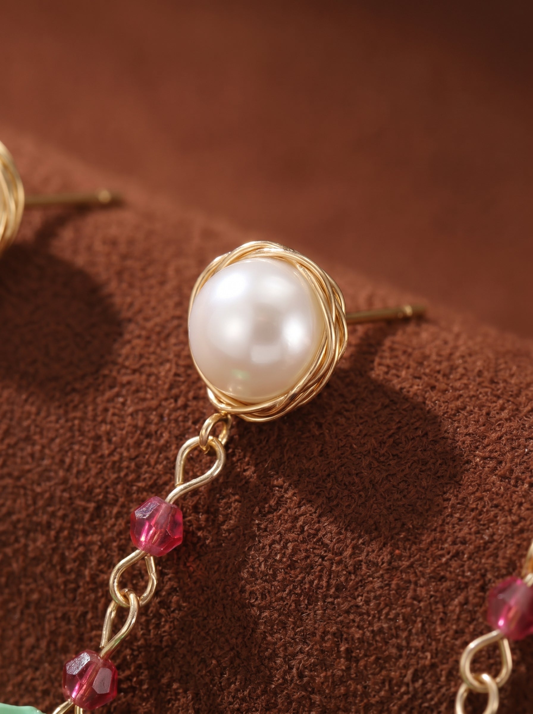 Close-up of Awaken Freshwater Pearl Flower Dangle Earrings featuring a white pearl stud wrapped in gold wire, a delicate gold chain with pink beads, and a mint green flower pendant. @pearl