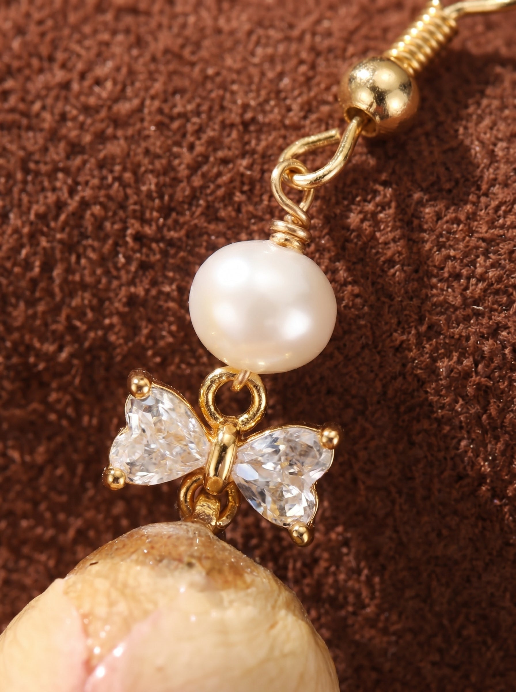 Botanical Dew earrings featuring a lustrous white pearl, a gold bow with clear cubic zirconia stones, and a preserved dried flower element.@pearl