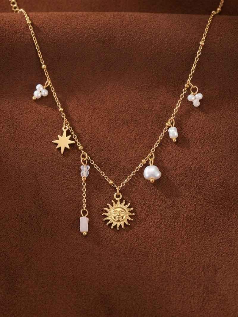 Gold-toned chain necklace with a sun pendant, a star charm, and several floating baroque freshwater pearls and pink quartz beads.