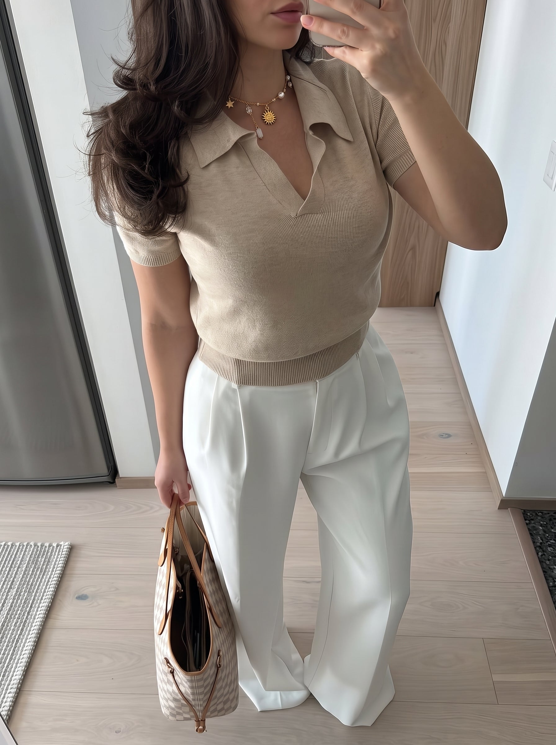 Collier Celestial Charm avec un pendentif soleil doré, une breloque étoile, et des perles d'eau douce flottantes, porté par une femme en polo beige et pantalon blanc. @lifestyle