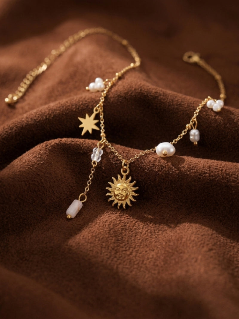 Gold-toned celestial necklace featuring a sun pendant, a star charm, and floating white freshwater pearls on a delicate chain.