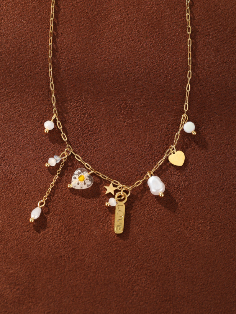 Gold-tone chain necklace with floating freshwater baroque pearls, a star charm, a heart charm, and a LOVE engraved tag.