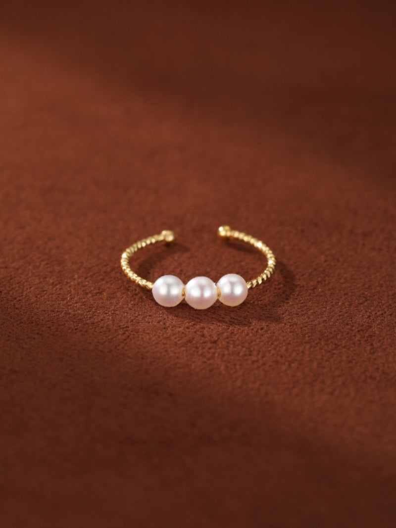 Continuum cuff ring with a twisted gold band and three 4mm white freshwater pearls set in an open design.