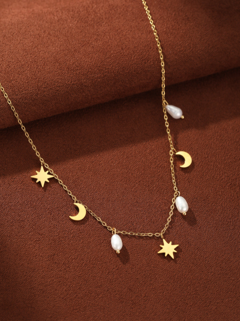 A delicate gold-tone chain necklace featuring alternating freshwater pearls and polished celestial charms including stars and crescent moons.