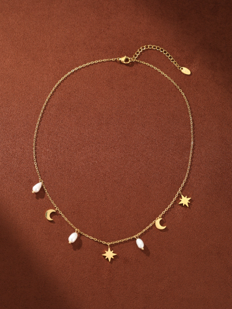 Delicate gold-tone chain necklace featuring small polished crescent moon and star charms interspersed with irregular white freshwater seed pearls. The necklace has an adjustable clasp and extension chain. @pearl