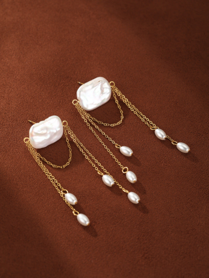 Driftfall freshwater pearl fringe drop earrings with gold chains and multiple small white pearl drops, set against a brown background.