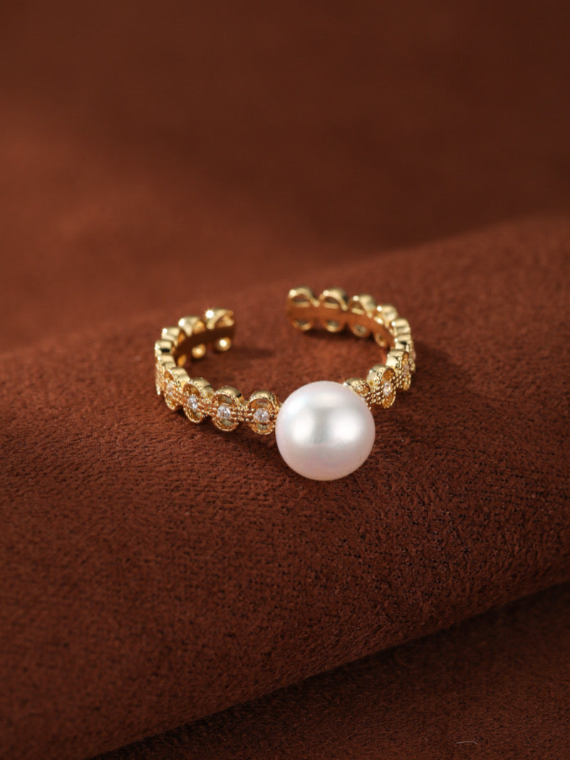 Gold-toned Ecliptic cuff ring with a single white freshwater pearl and sparkling accent details.