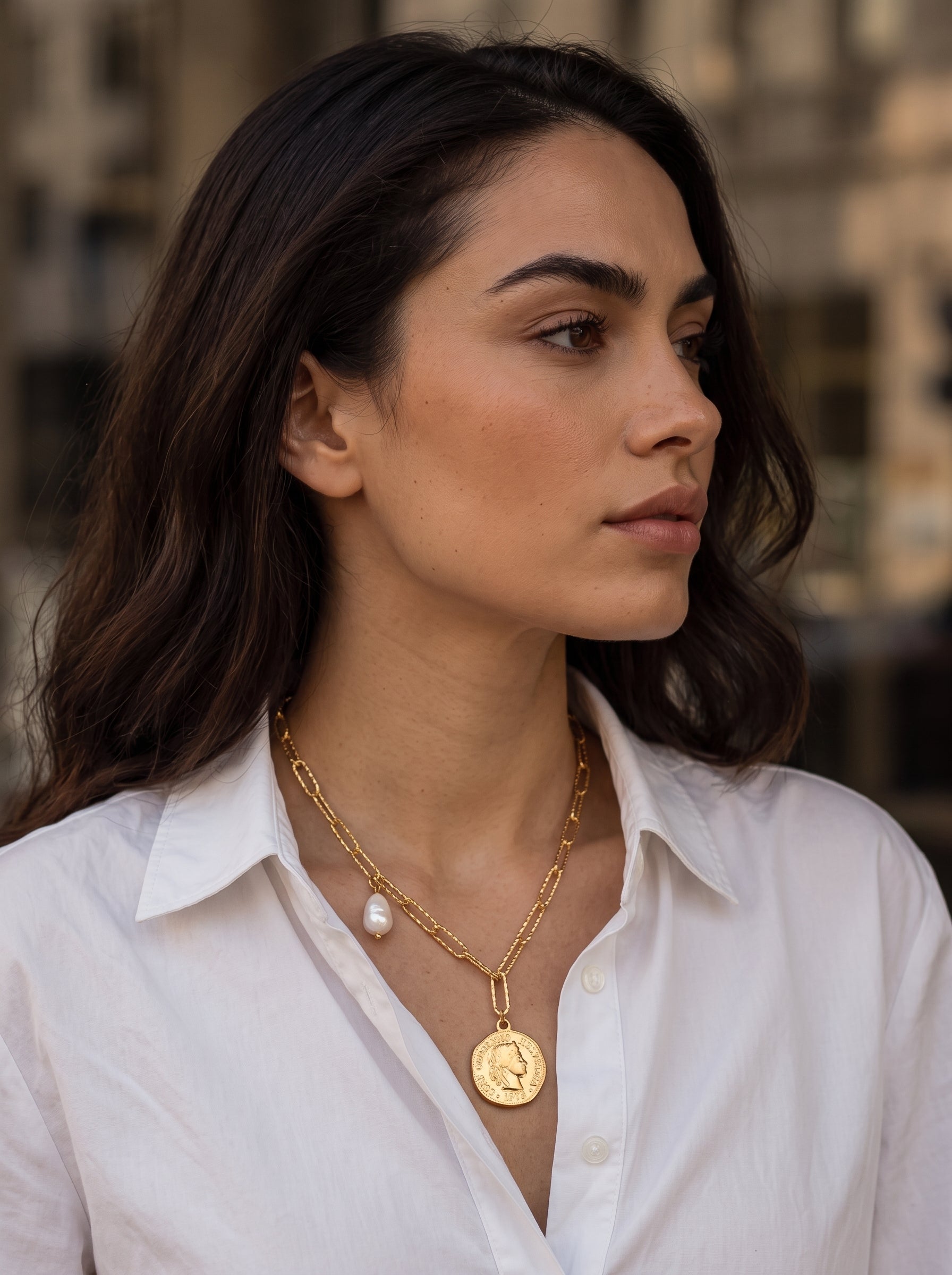 Une femme porte un collier à chaîne à maillons imposants doré avec un pendentif pièce et une seule perle blanche d'eau douce pendante. @lifestyle