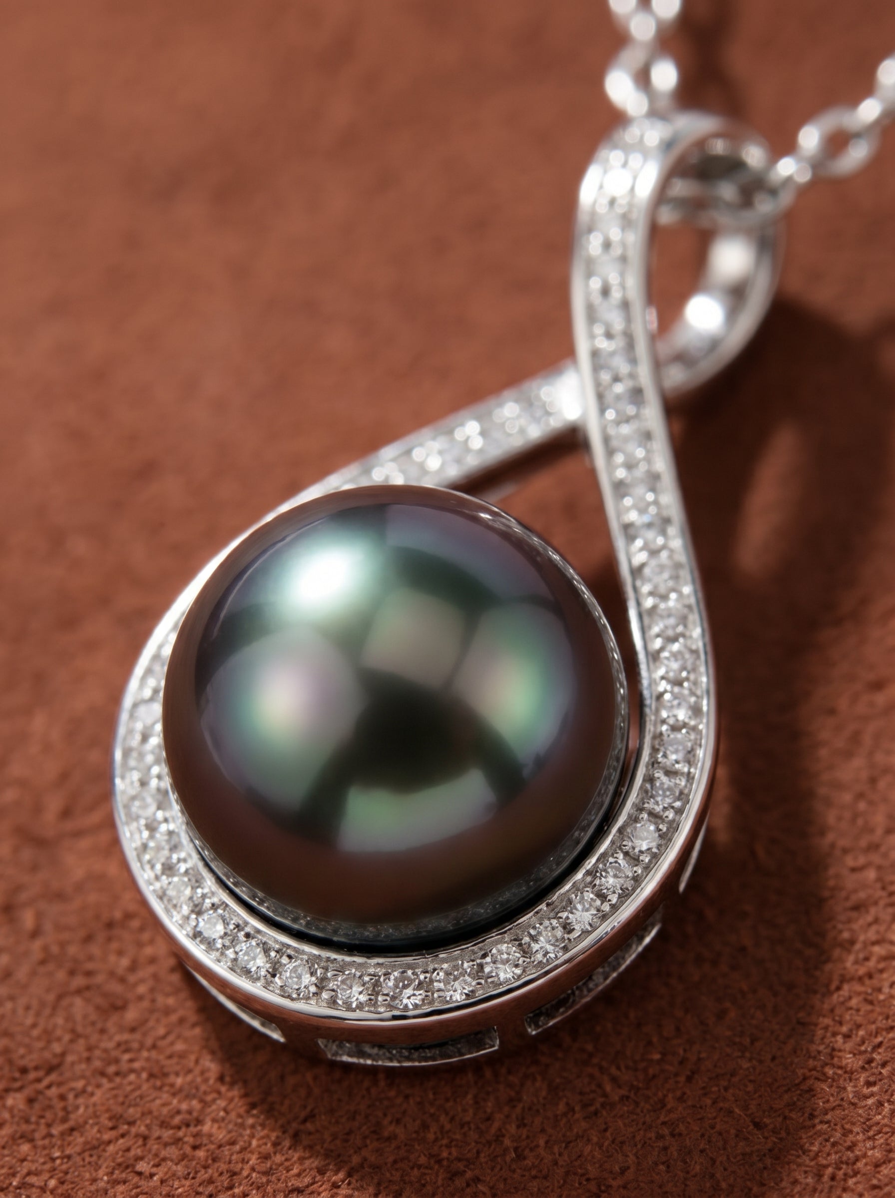Close-up of the Eternity Weave Tahitian Pearl Infinity Drop Necklace, featuring a lustrous 10mm round Tahitian pearl with peacock overtones, embraced by a polished silver-toned infinity symbol frame encrusted with sparkling accents.@pearl