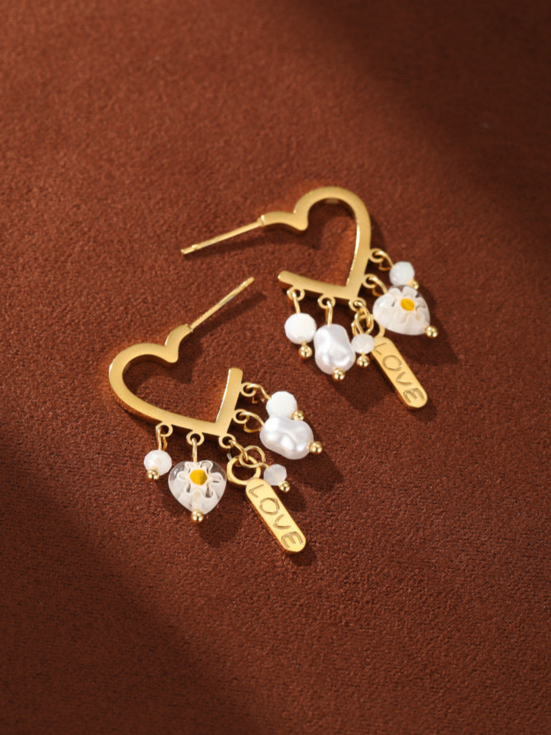 Boucles d'oreilles goutte cœur dorées présentant des perles d'eau douce, des perles florales, et des breloques « LOVE ».