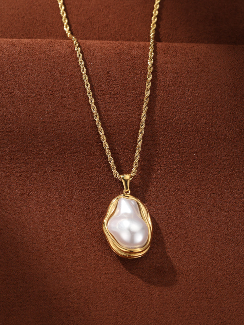 A gold-toned chunky rope chain necklace with a large, irregularly shaped white freshwater pearl pendant in a fluid gold setting. @pearl