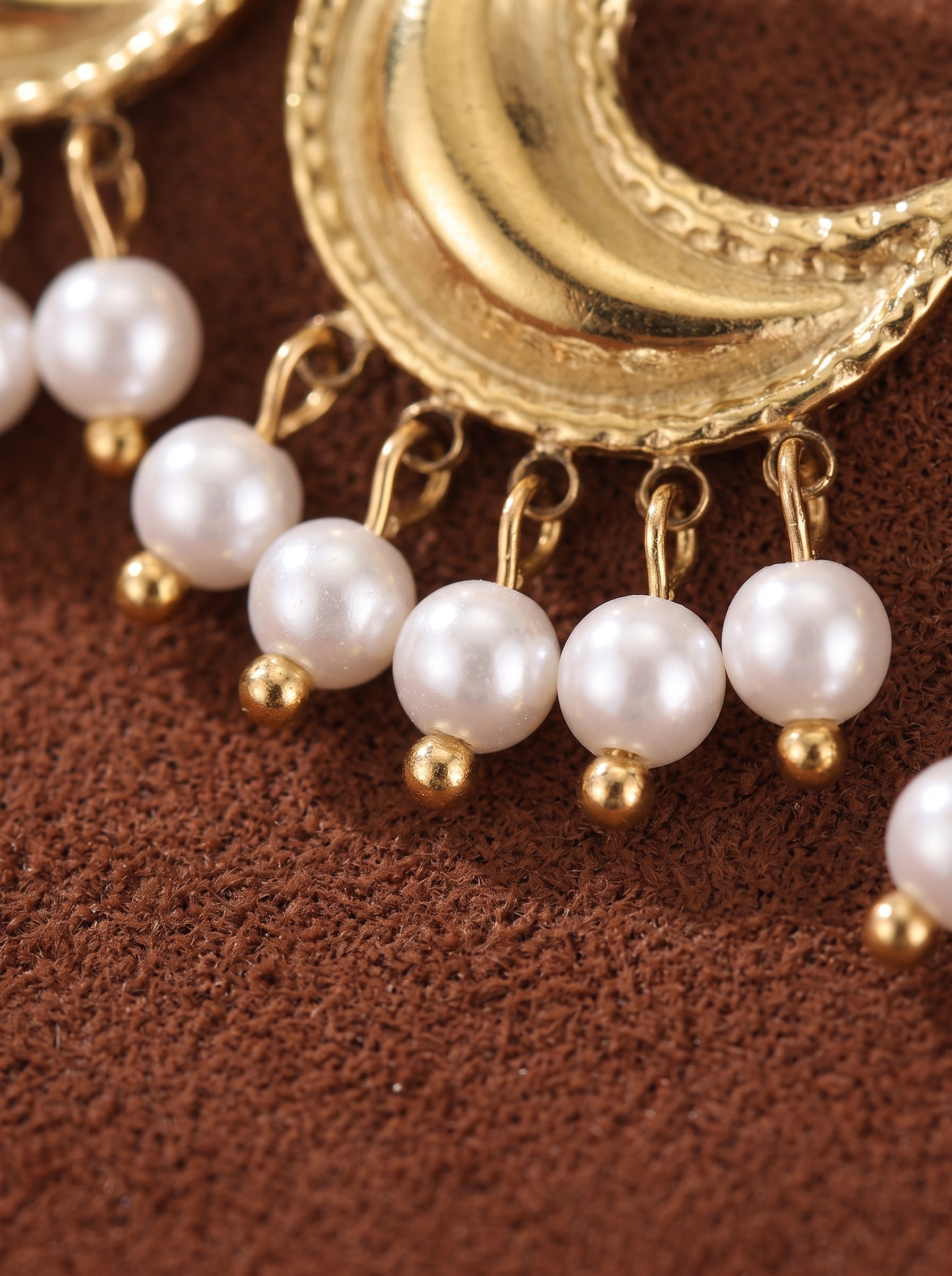 Close-up of Halcyon gold-tone moon drop earrings featuring five dangling white freshwater pearls on each earring, with a textured crescent moon top. @perle