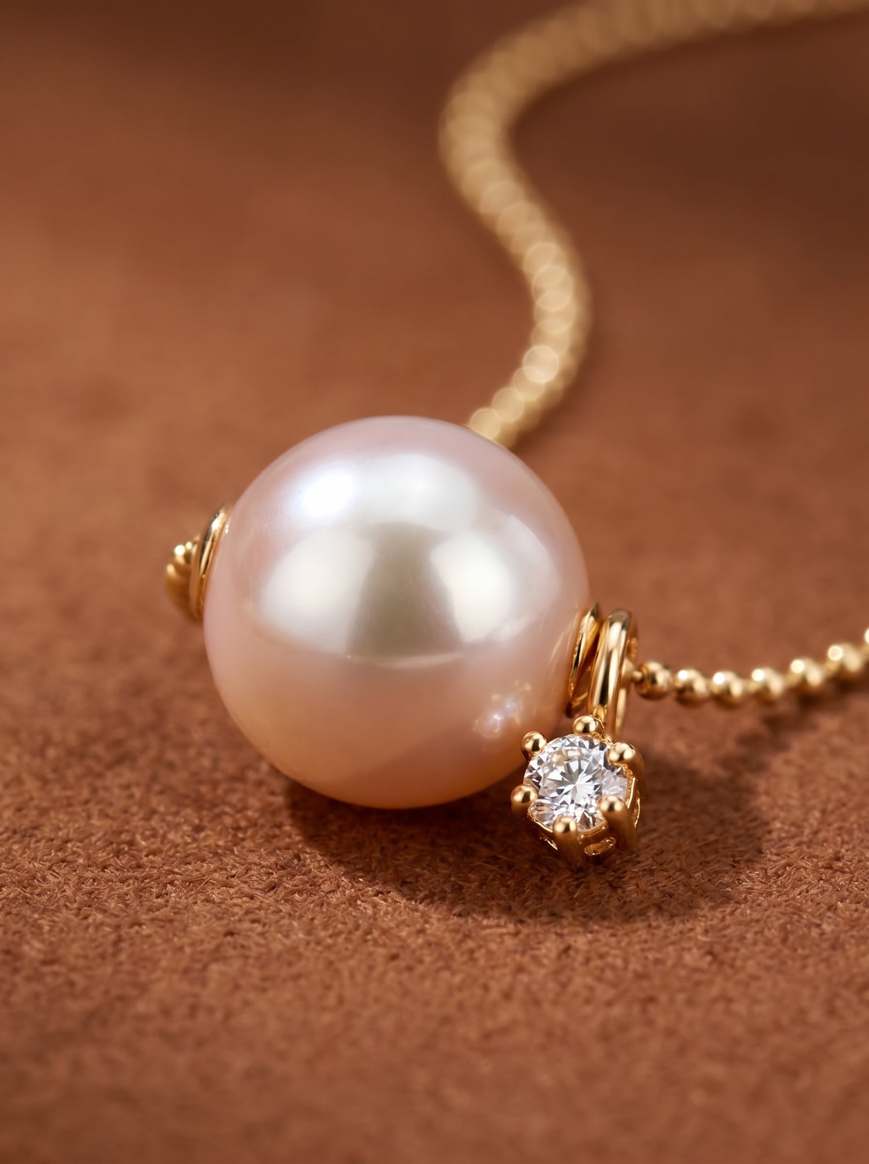 A close-up of a Halo Akoya pearl necklace featuring a single 8mm white Akoya pearl with pink overtones, suspended on a delicate gold chain, accented by a sparkling diamond star. @pearl