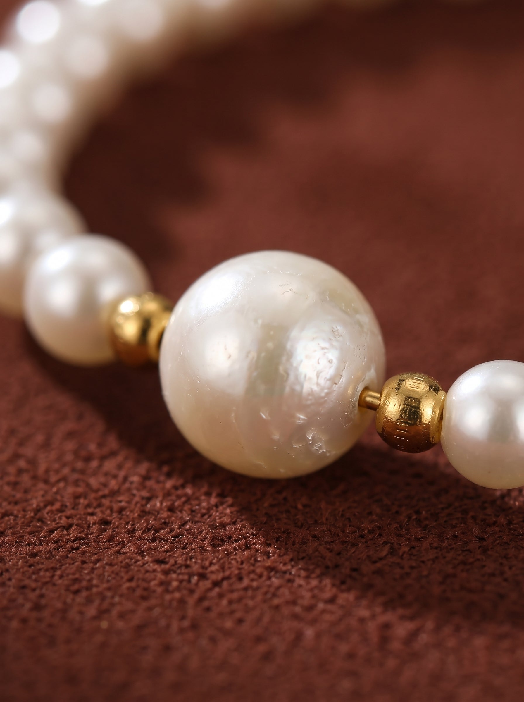 Close-up of a white freshwater pearl beaded bracelet with gold-toned accents and a central heart charm. @pearl