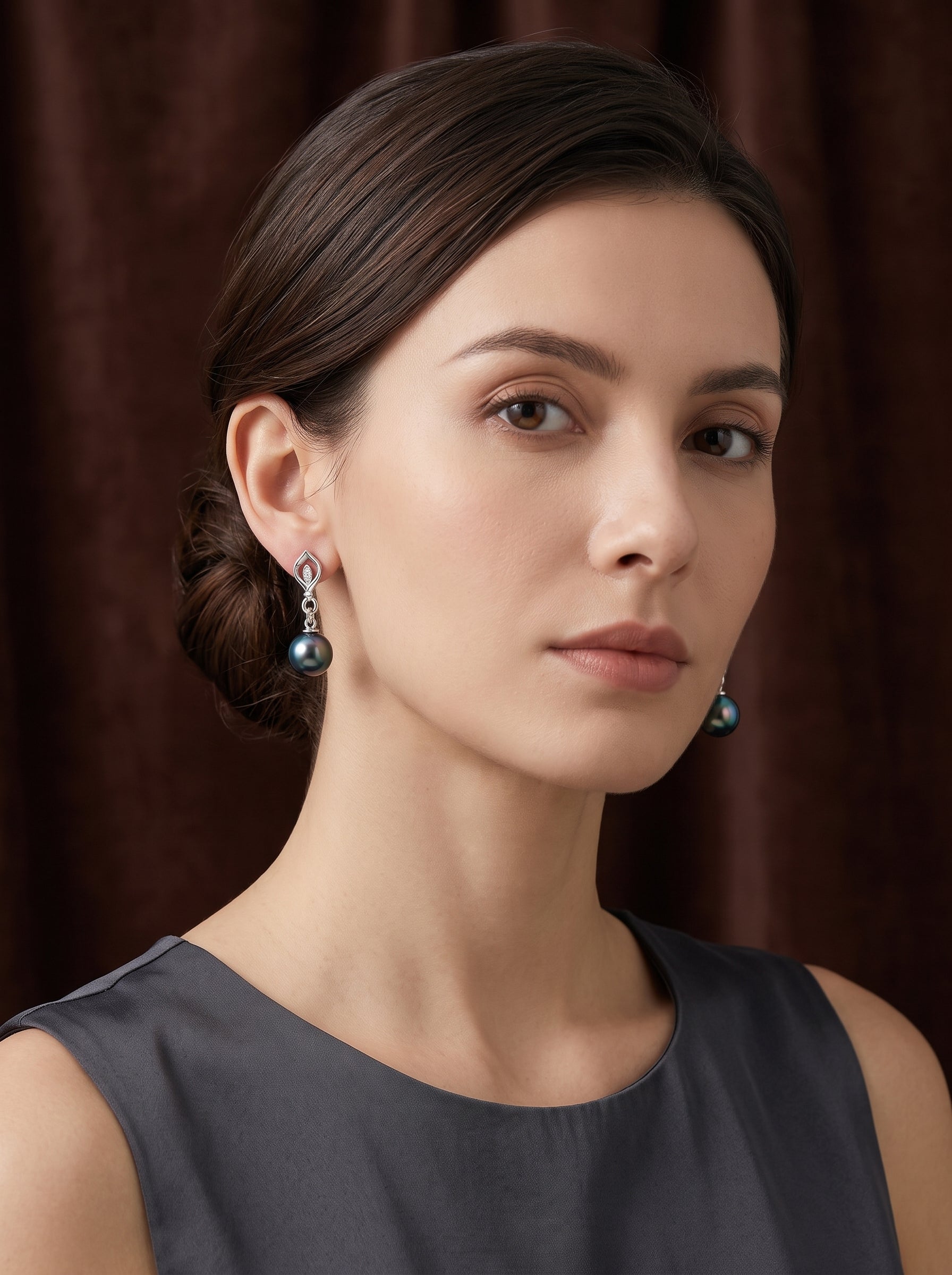 Mannequin portant les boucles d'oreilles goutte feuille diamant en perle de Tahiti Ignis, présentant une lustrée perle noire suspendue à un motif feuille accentué de diamants.@model