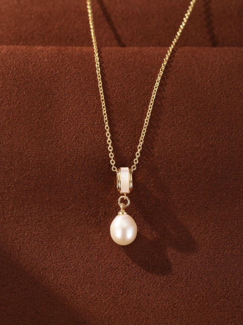 A delicate gold-toned chain necklace featuring a single, luminous 8mm white freshwater pearl drop pendant with a modern cylindrical accent.