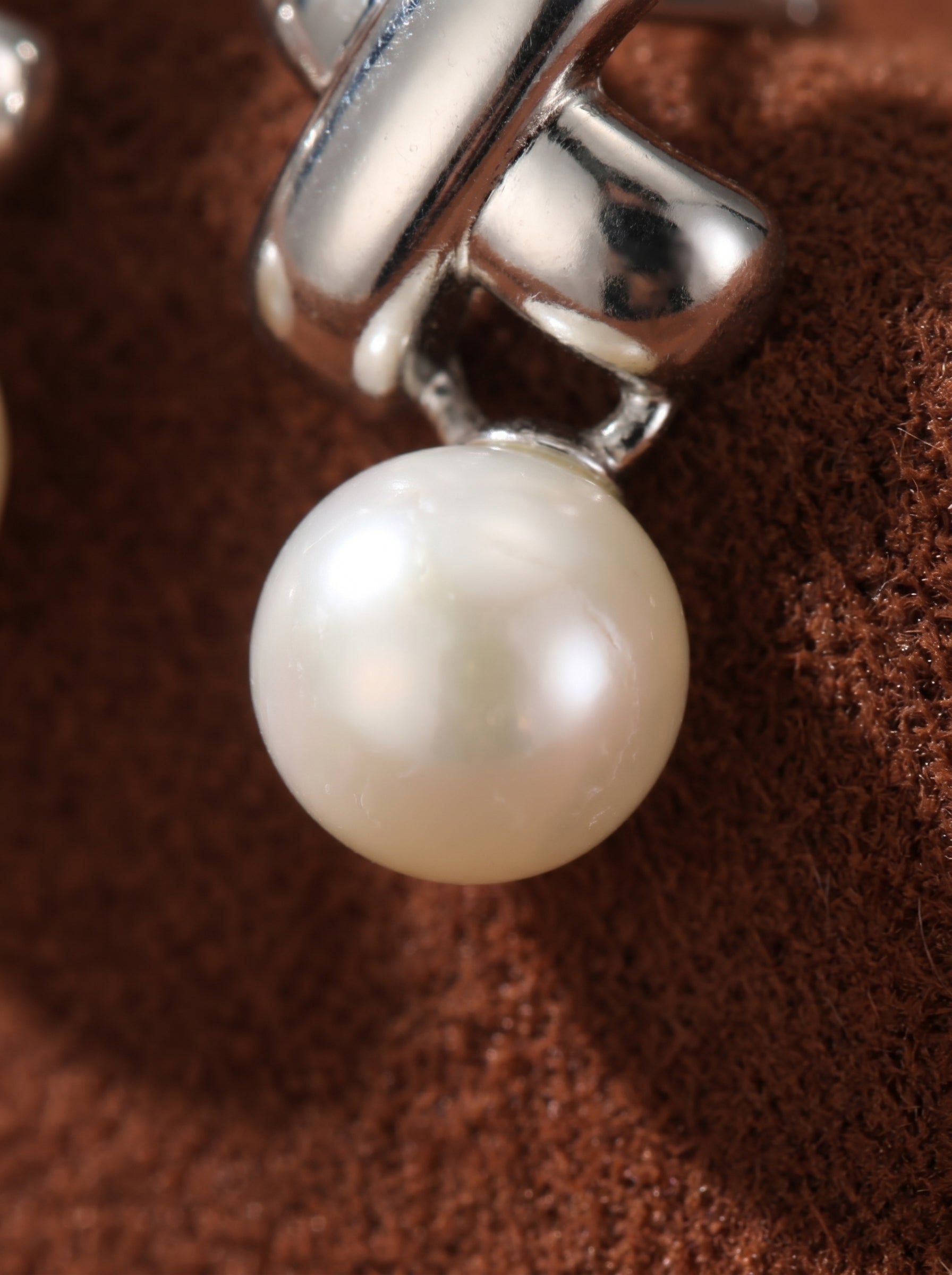 Close-up of the Interweave Freshwater Pearl Cross Drop Earrings, showcasing a polished silver-toned cross stud with a lustrous white button pearl dangling below. @pearl