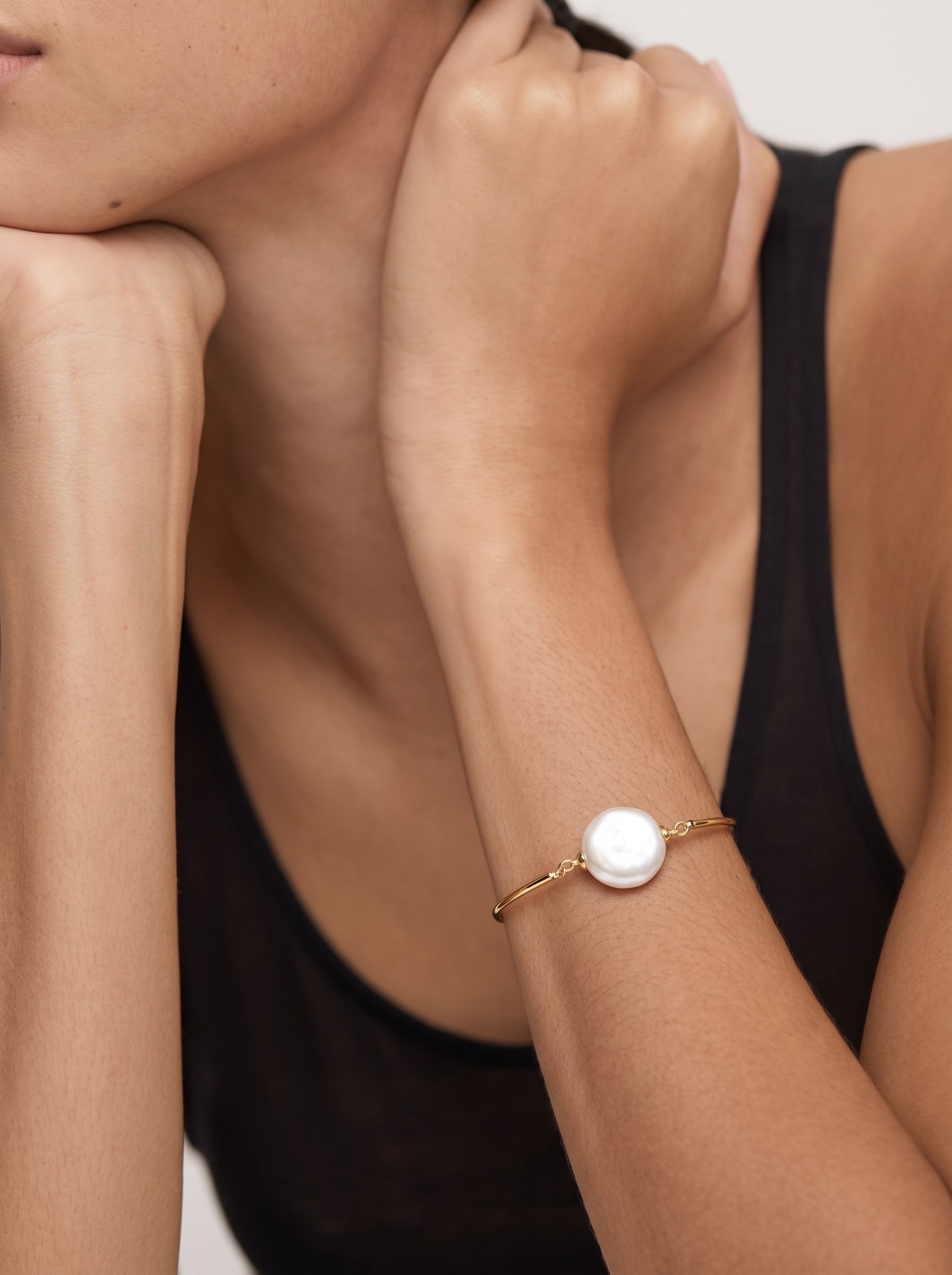 Close-up of a woman's arm wearing the Keystone Freshwater Pearl Floating Chain Bracelet, featuring a large, luminous baroque pearl centered on a delicate gold chain. @model