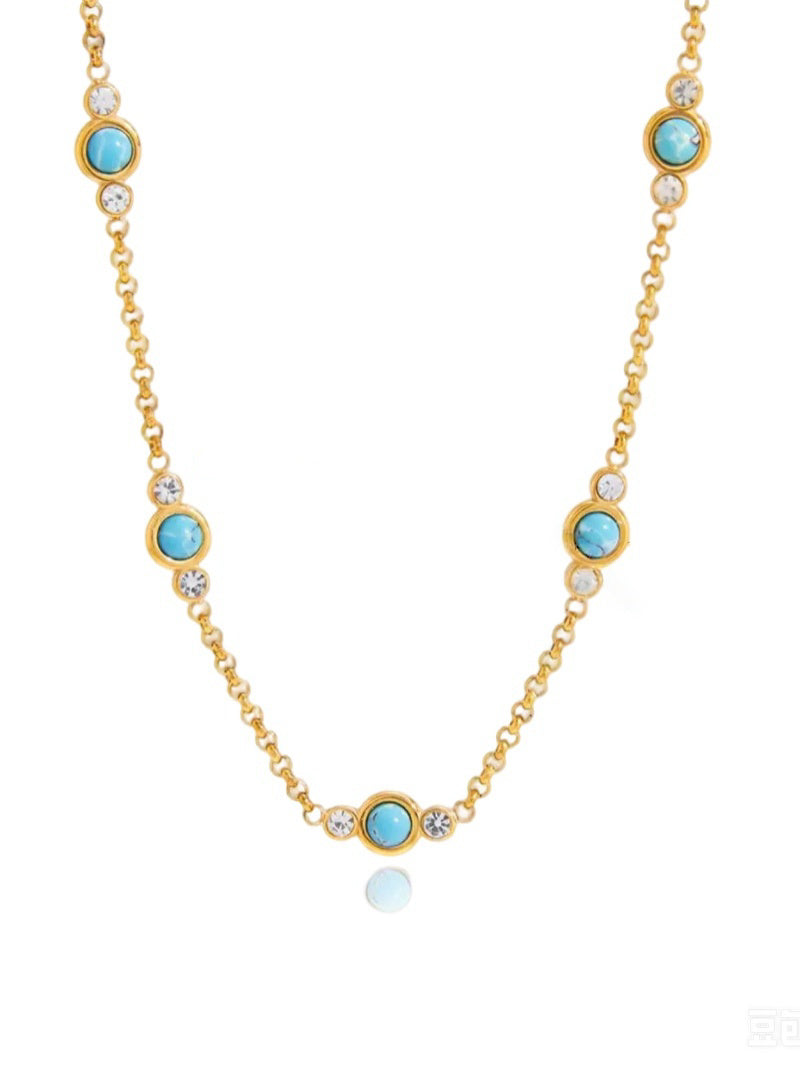 Gold-tone layered necklace with turquoise beads and clear cubic zirconia stones.