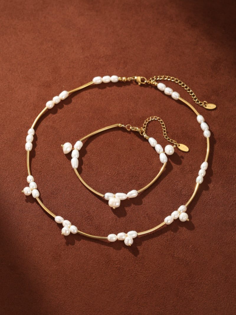 Gold choker necklace and bracelet set featuring clusters of small white freshwater pearls on a brown background. @pearl