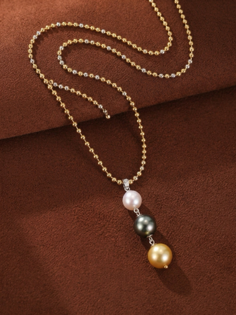 Luminance necklace with three round pearls: a white Akoya, a black Tahitian, and a golden South Sea pearl, suspended from a long, two-tone gold and silver ball chain.