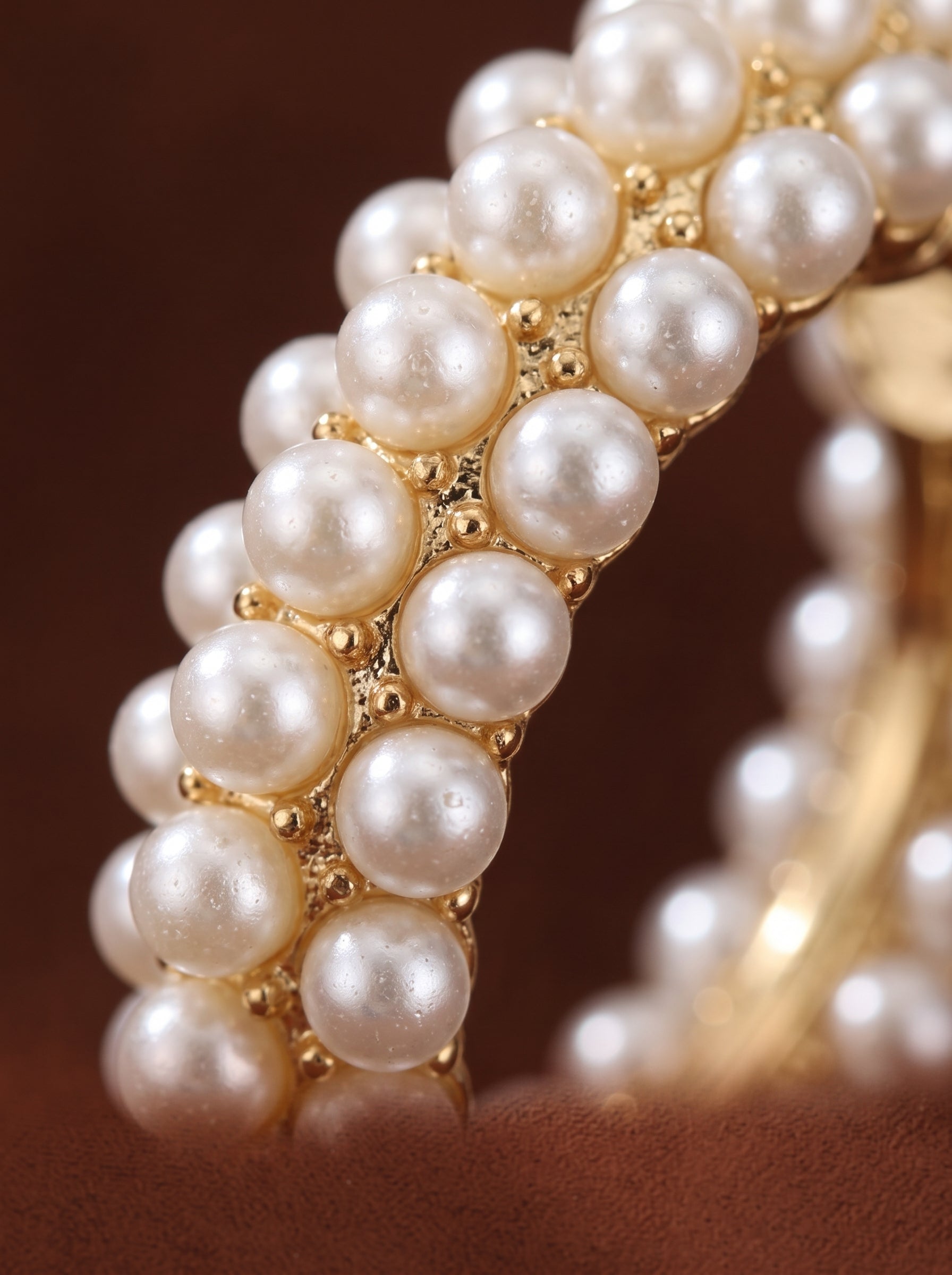 Close-up of Luminous Bloom chunky hoop earrings adorned with multiple rows of lustrous white imitation pearls on a gold-toned base. @pearl