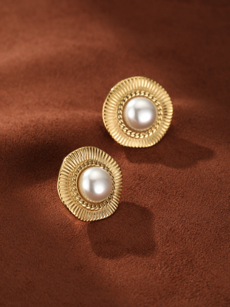 A pair of Meridian Shine gold-toned stud earrings featuring a central lustrous white freshwater pearl surrounded by a textured sunburst-inspired frame and a delicate chain-link detail.