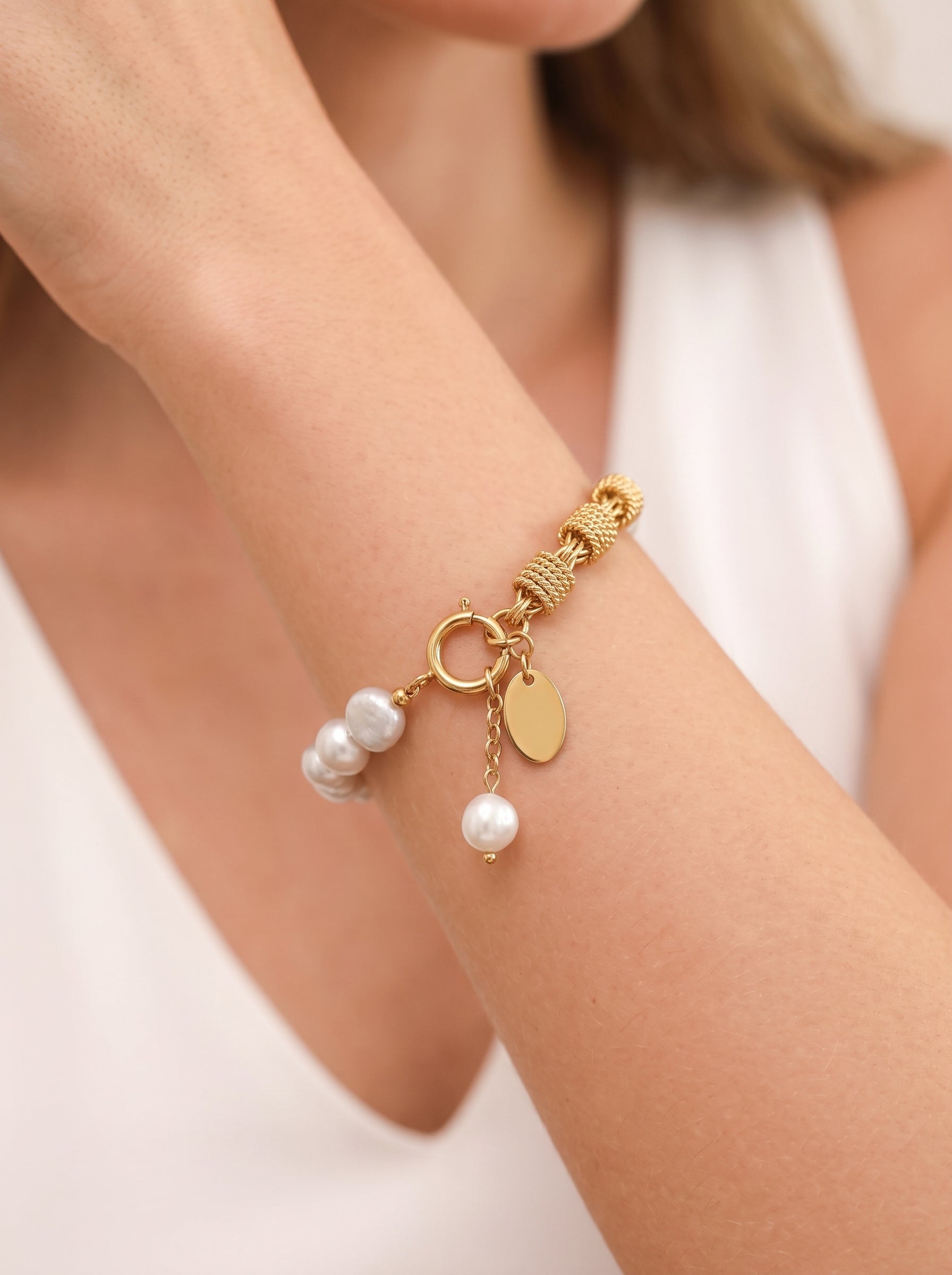 Gold-toned Mesh Weave bracelet featuring a chunky chain and a strand of luminous freshwater pearls, with a dangling pearl charm and a blank oval tag. The bracelet is worn on a model's wrist. @model