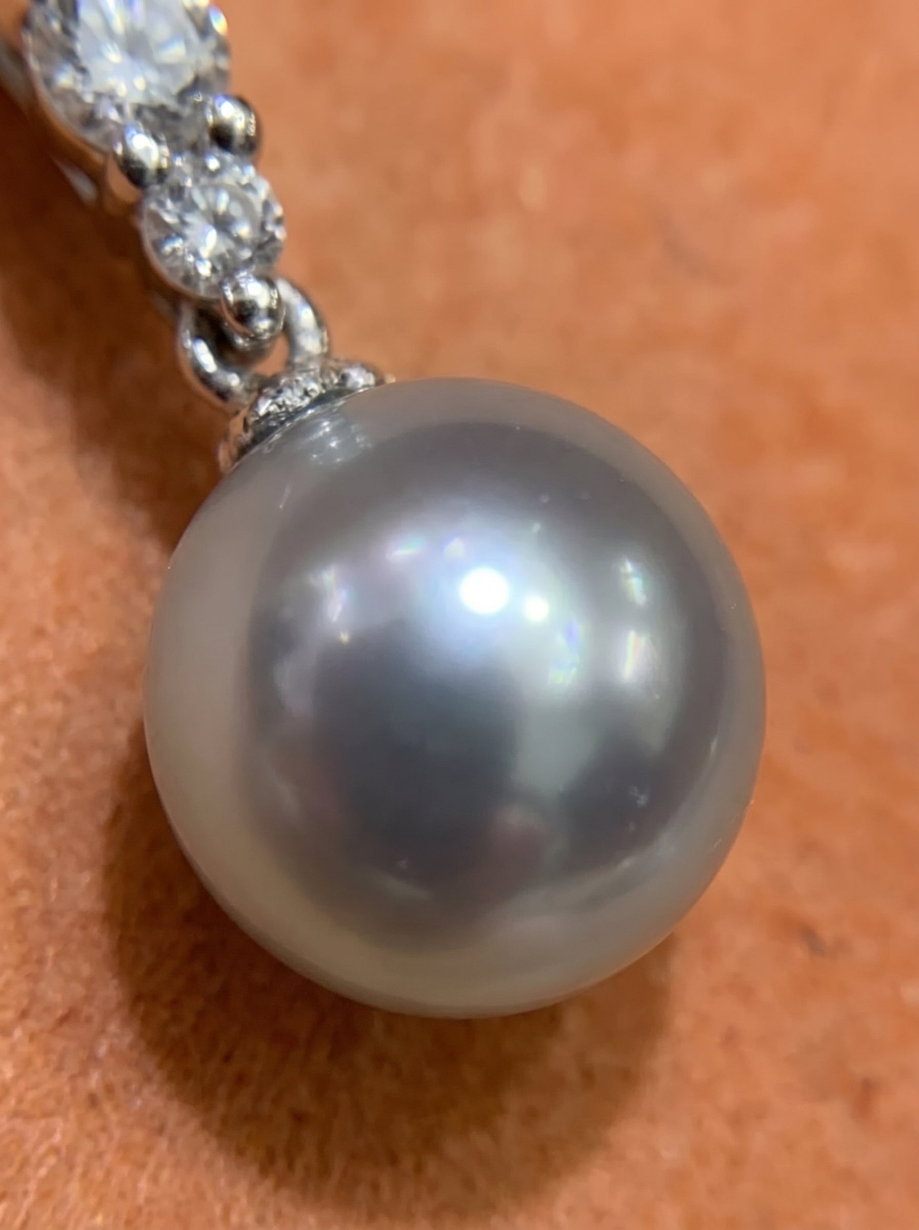 Close-up of a lustrous 9mm round silver Akoya pearl with sparkling diamonds on a delicate chain, part of the Moonbeam necklace. @pearl