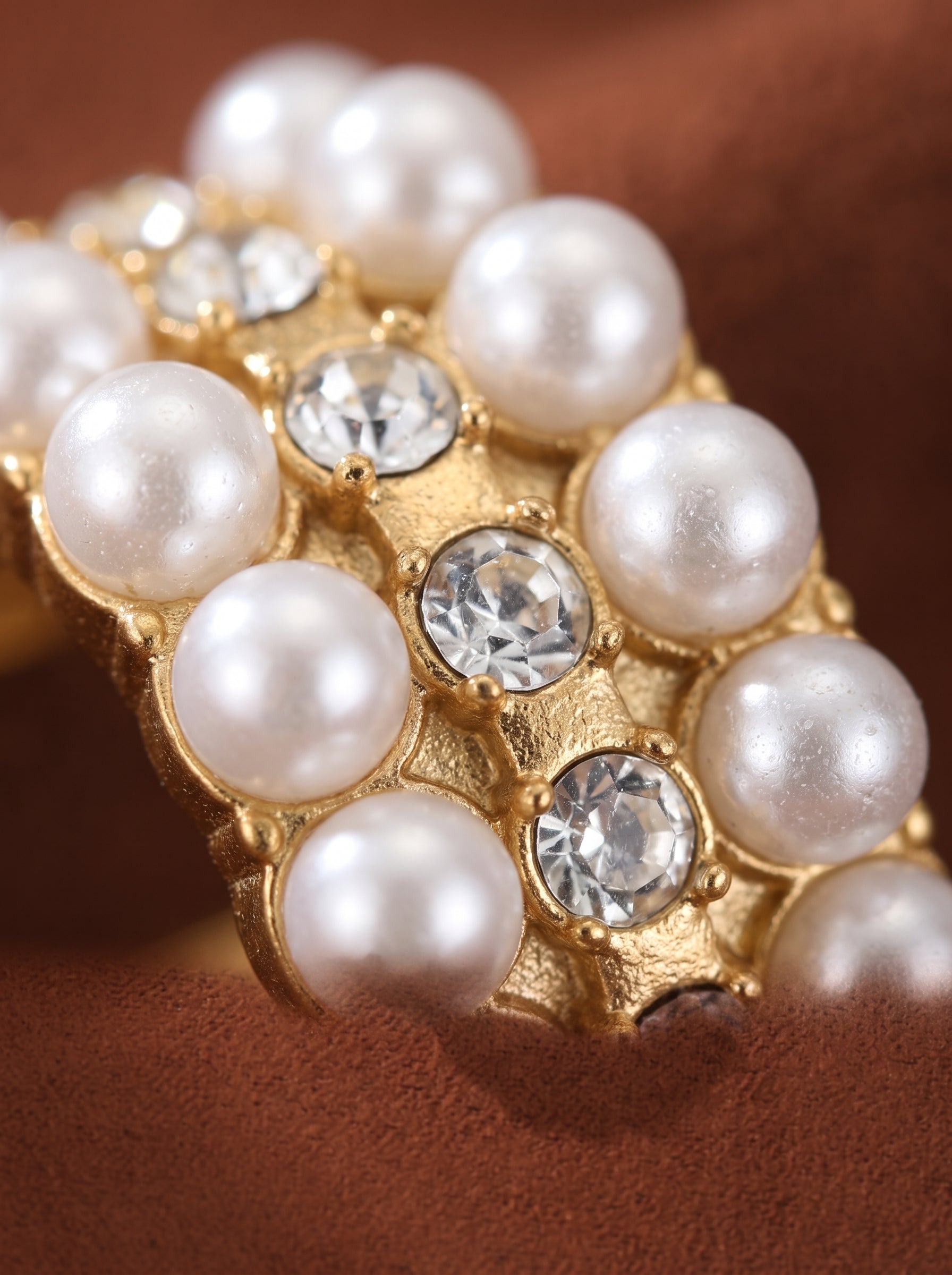 Close-up of a gold hoop earring featuring multiple rows of lustrous 3mm freshwater white button pearls and sparkling crystals. @pearl