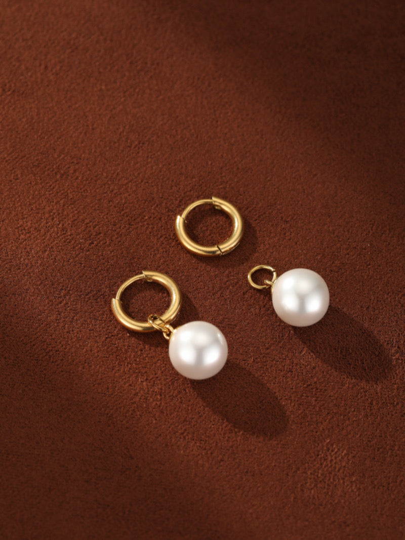 Une paire de créoles pendantes ton or, chacune avec une lustrée perle blanche d'eau douce pendant de la créole.