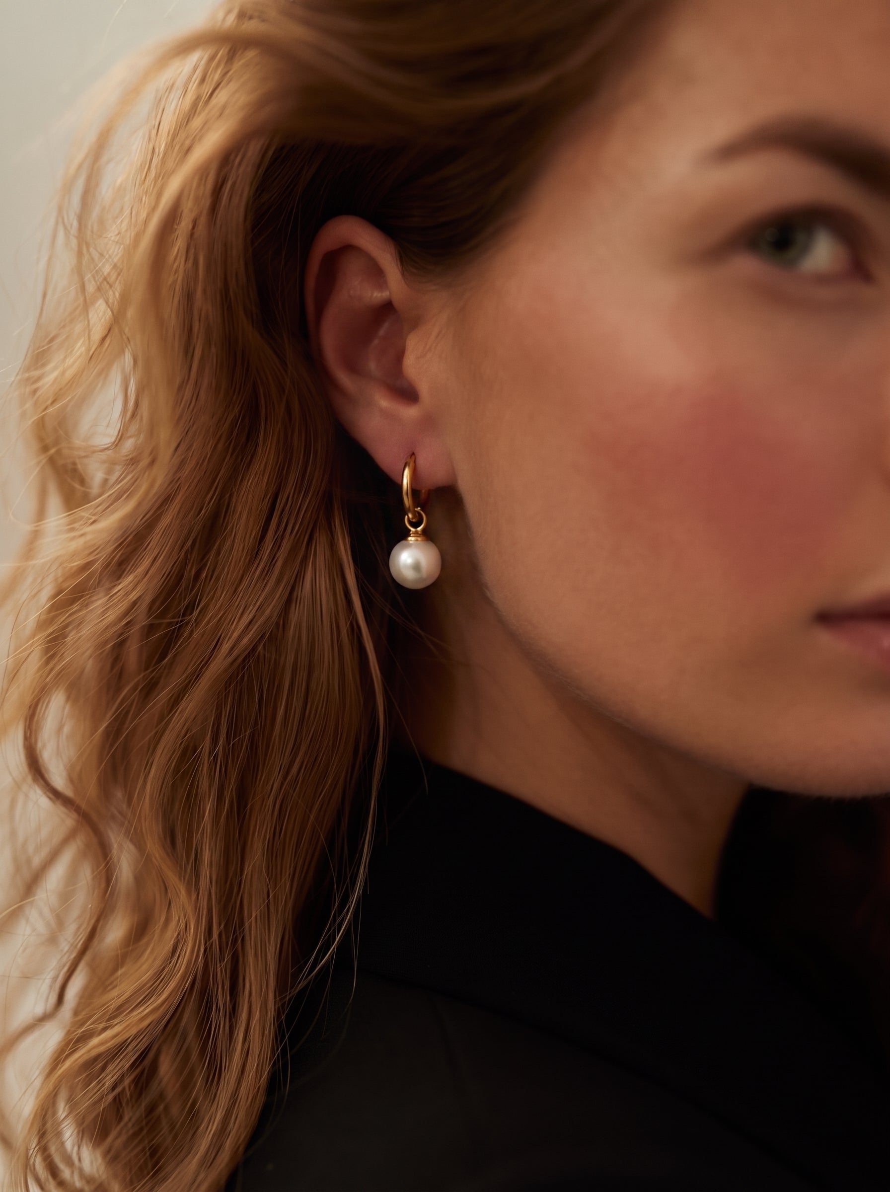 Une créole dorée avec une seule perle pendante blanche d'eau douce est portée par une femme. @model