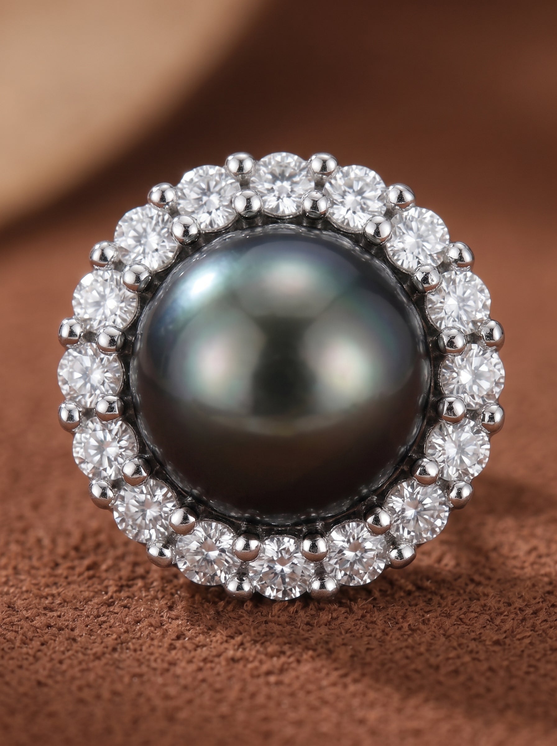 Gros plan d'une boucle d'oreille puce Shadowlight présentant une lustrée perle noire ronde de Tahiti de 10 mm entourée d'un halo de pierres accent transparentes taille brillant. @pearl