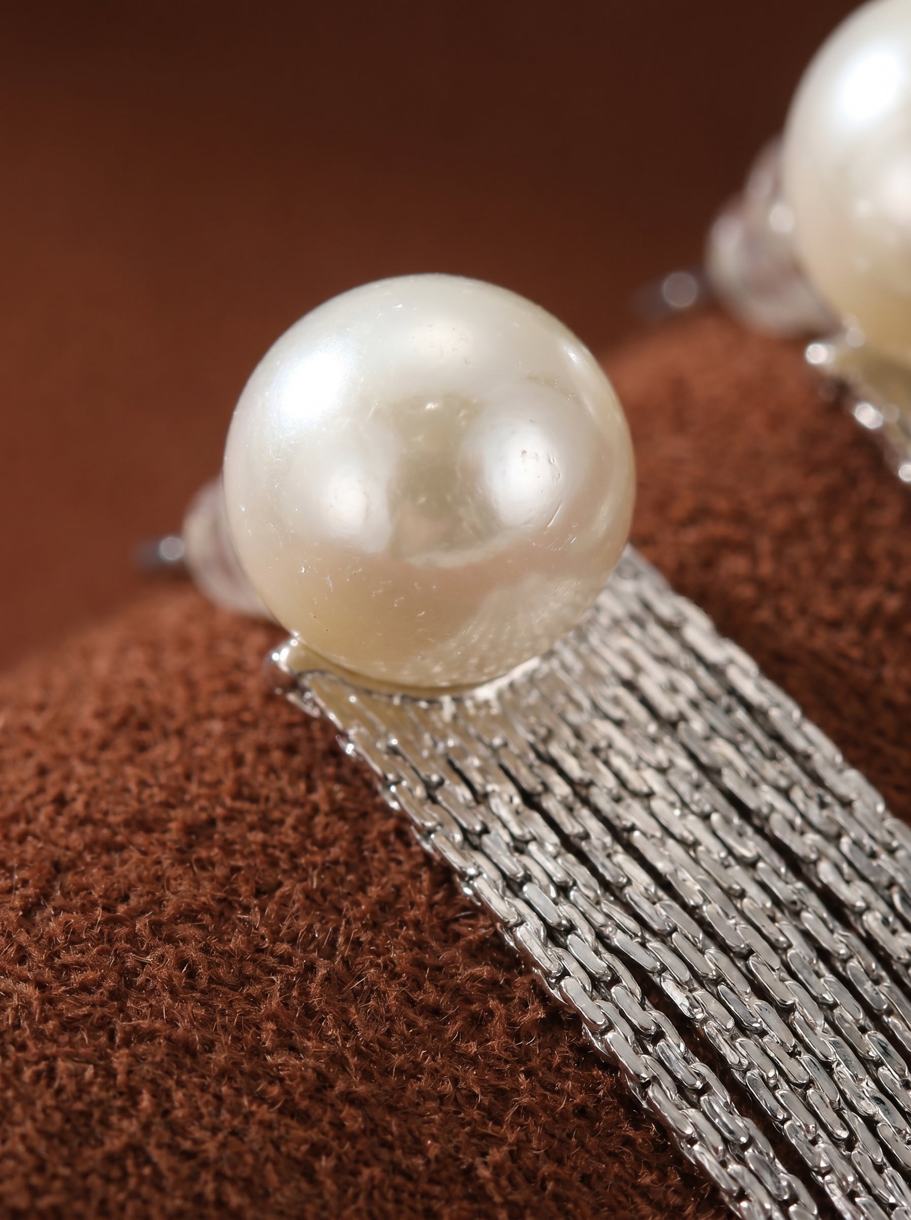 Close-up of a Shimmer Freshwater Pearl Fringe Dangle Earring, featuring a lustrous baroque pearl stud and a cascade of silver-toned metallic fringe. @perle @pearl