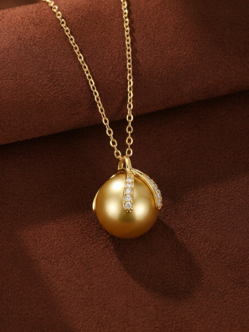 Solara pendant necklace featuring a 12mm golden South Sea pearl set in a polished gold-tone pendant with sparkling gemstone accents on a delicate gold chain.