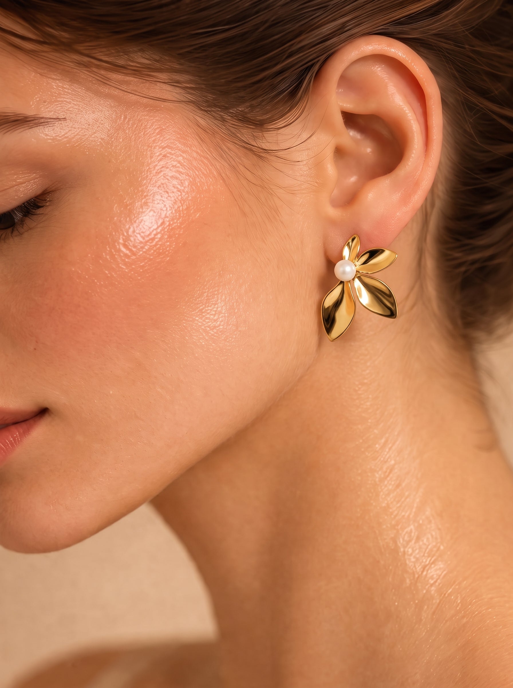 Gros plan de l'oreille d'une femme portant les boucles d'oreilles puces florales Sprout ton or avec une perle d'eau douce au centre. @model