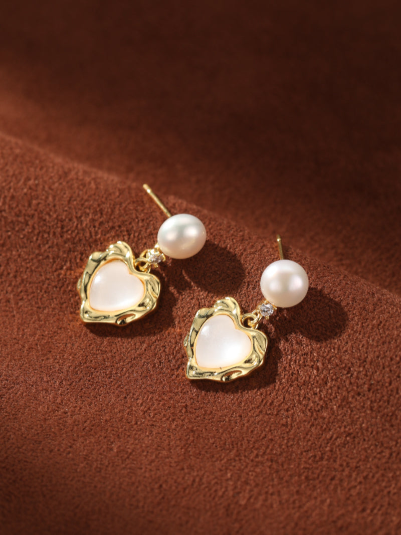 Starlight gold-tone stud drop earrings featuring a white freshwater pearl above a textured gold heart shape with a white inlay. @pearl