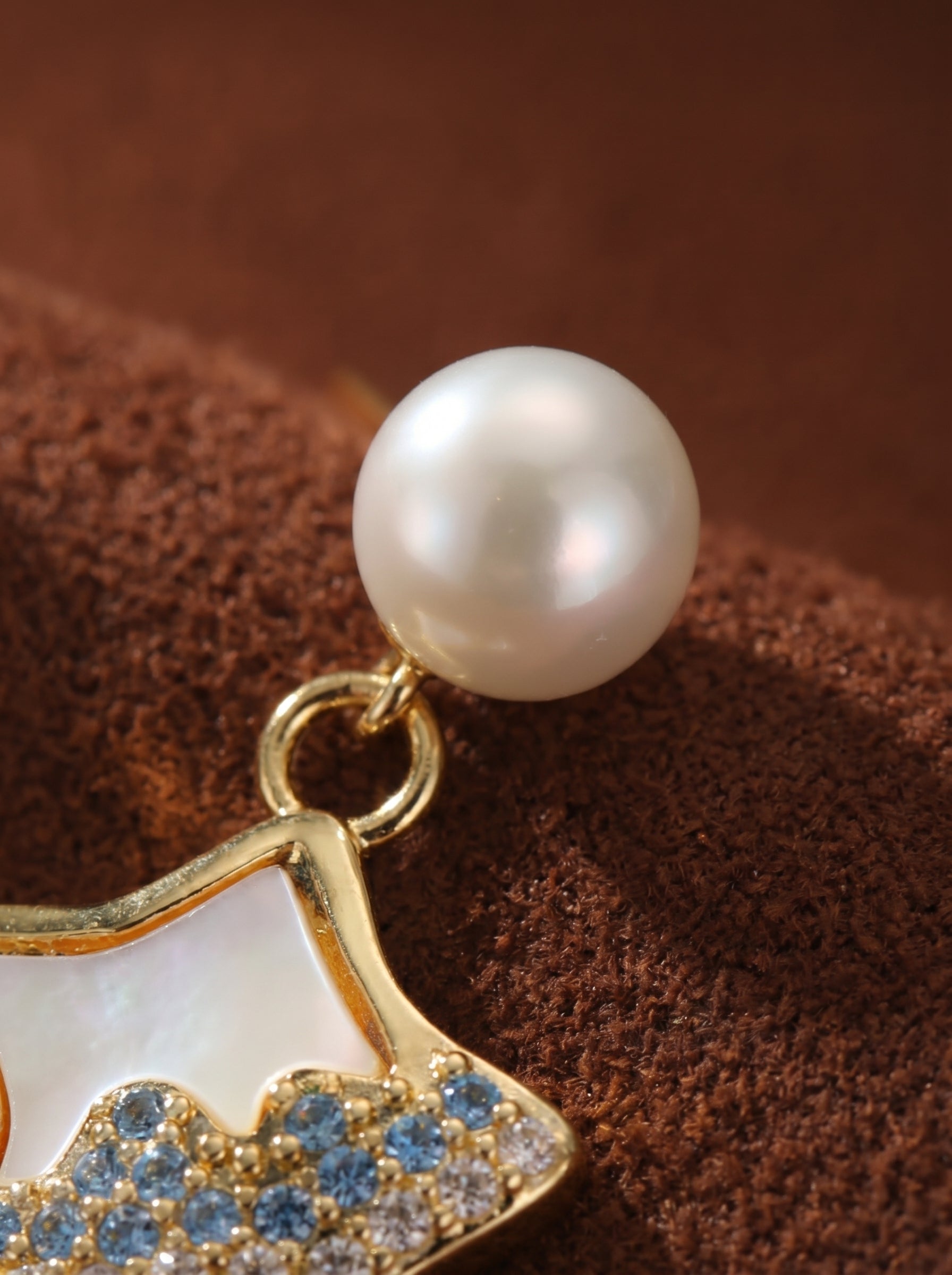 Close-up of a Starlight Freshwater Pearl Star Stud Drop Earring featuring a lustrous white pearl stud and a gold-tone star drop with mother-of-pearl inlay and blue and clear pavé accents. @pearl