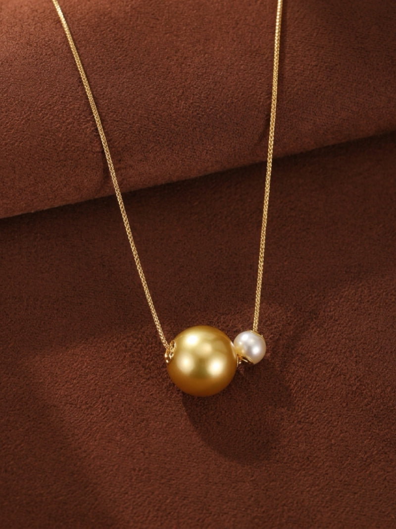 A delicate gold chain necklace featuring a large, lustrous golden South Sea pearl and a smaller, radiant white Akoya pearl side-by-side.