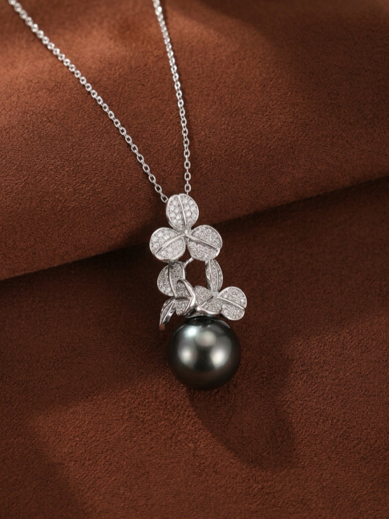 A close-up shot of the Unfold Tahitian Pearl Clover Pendant Necklace, featuring a cluster of diamond-encrusted clover shapes suspending a single, lustrous black Tahitian pearl.