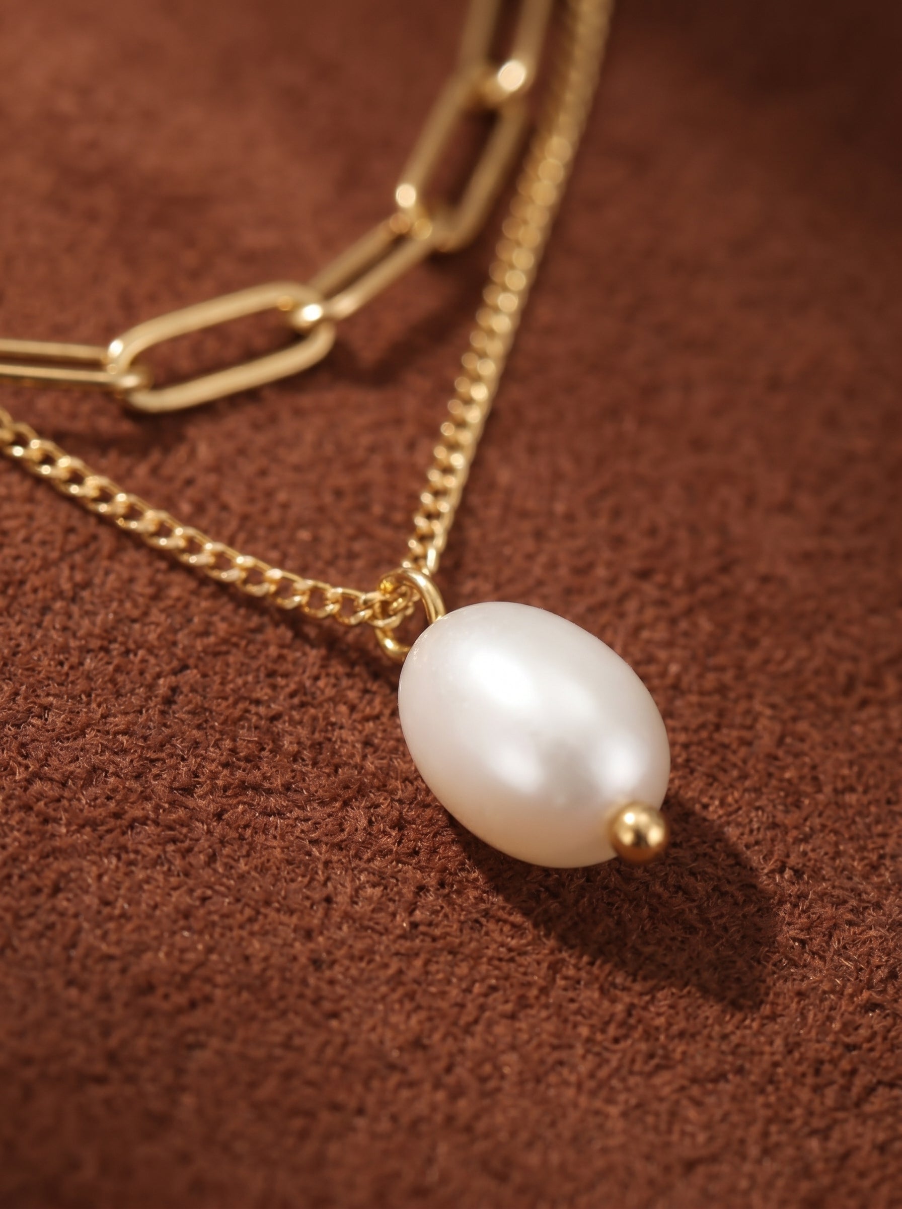 Gold-toned layered necklace featuring a delicate curb chain with a white freshwater pearl drop pendant and a larger paperclip chain above. @pearl