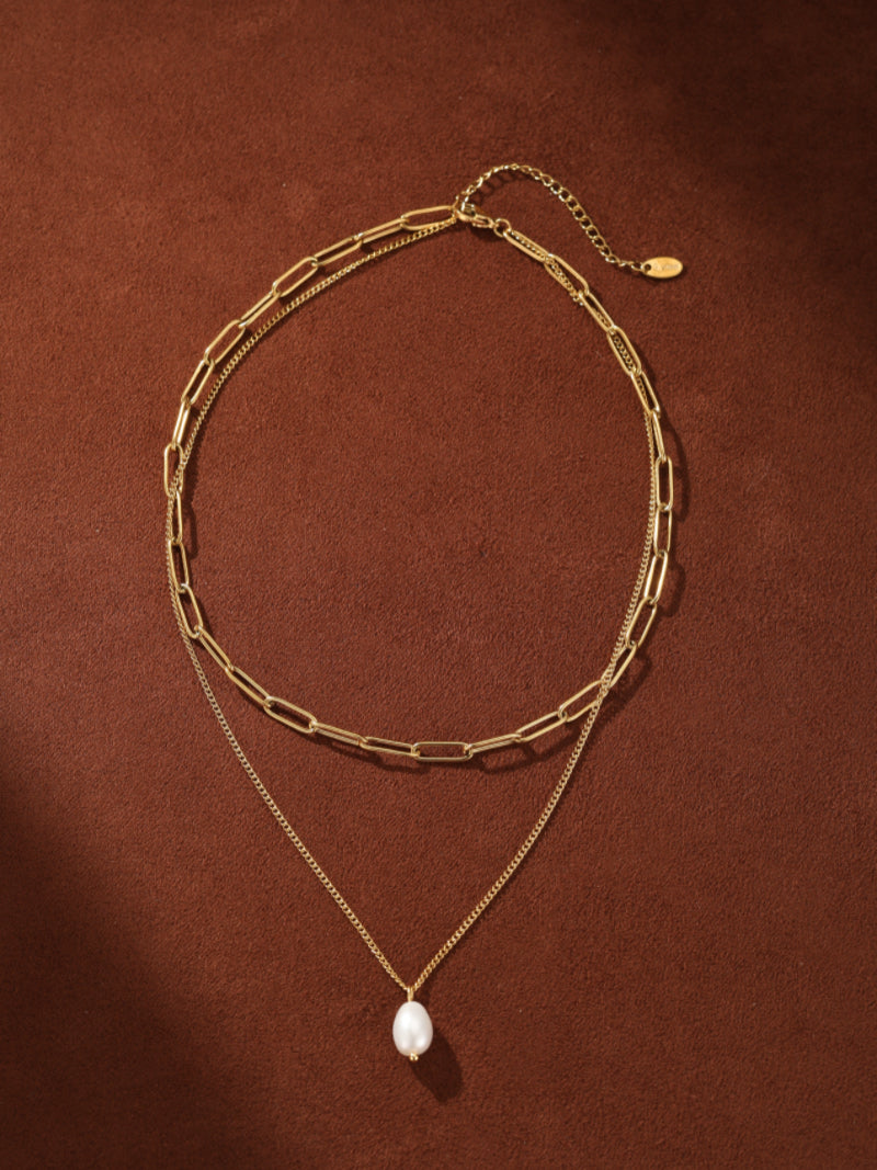 Gold-toned layered necklace with a thick paperclip chain and a thin curb chain, featuring a single white freshwater pearl drop pendant. @pearl