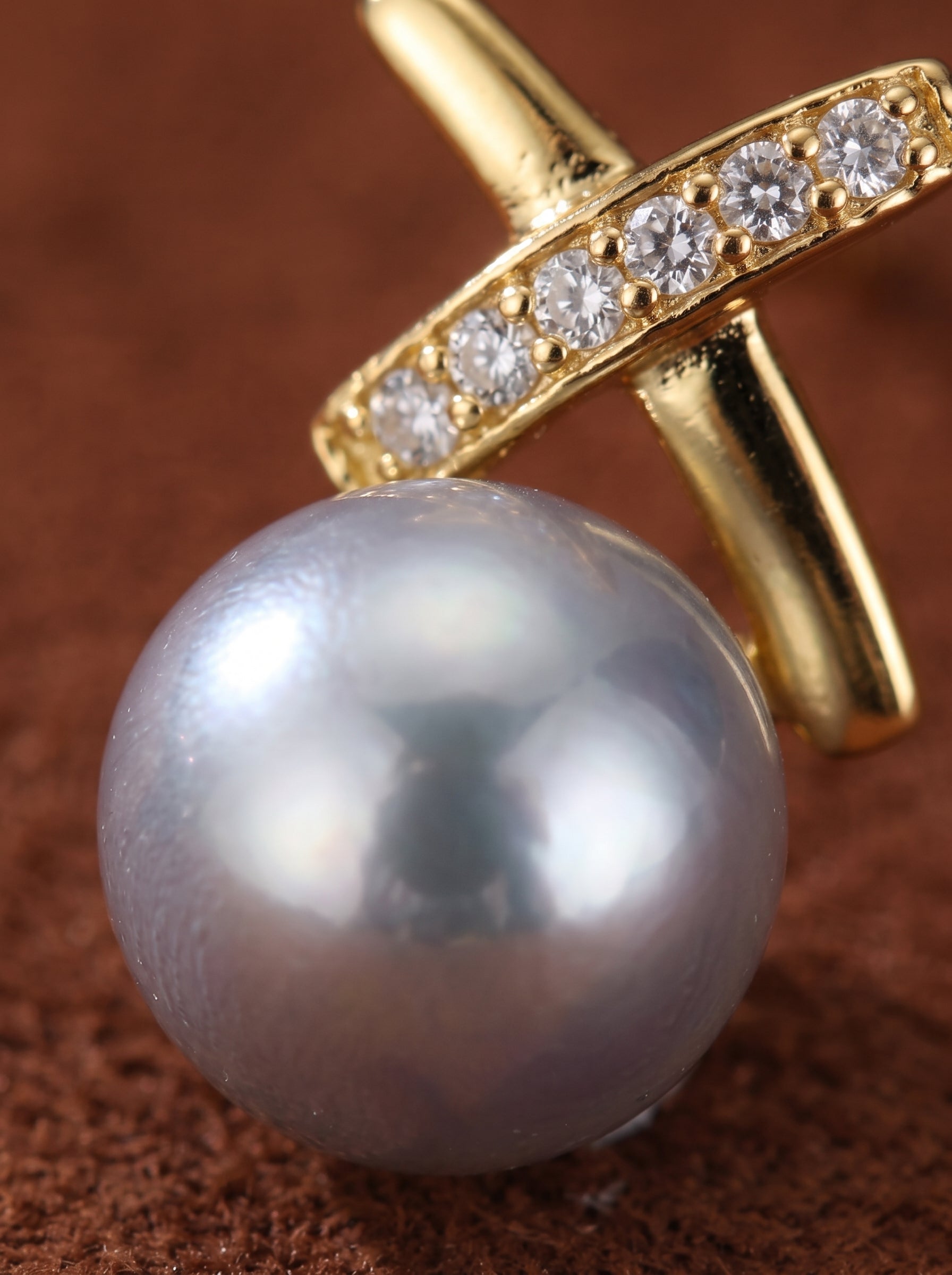 Close-up of a Veritas Akoya pearl stud earring featuring a gold-toned cross design adorned with sparkling crystals and a lustrous pearl. @pearl