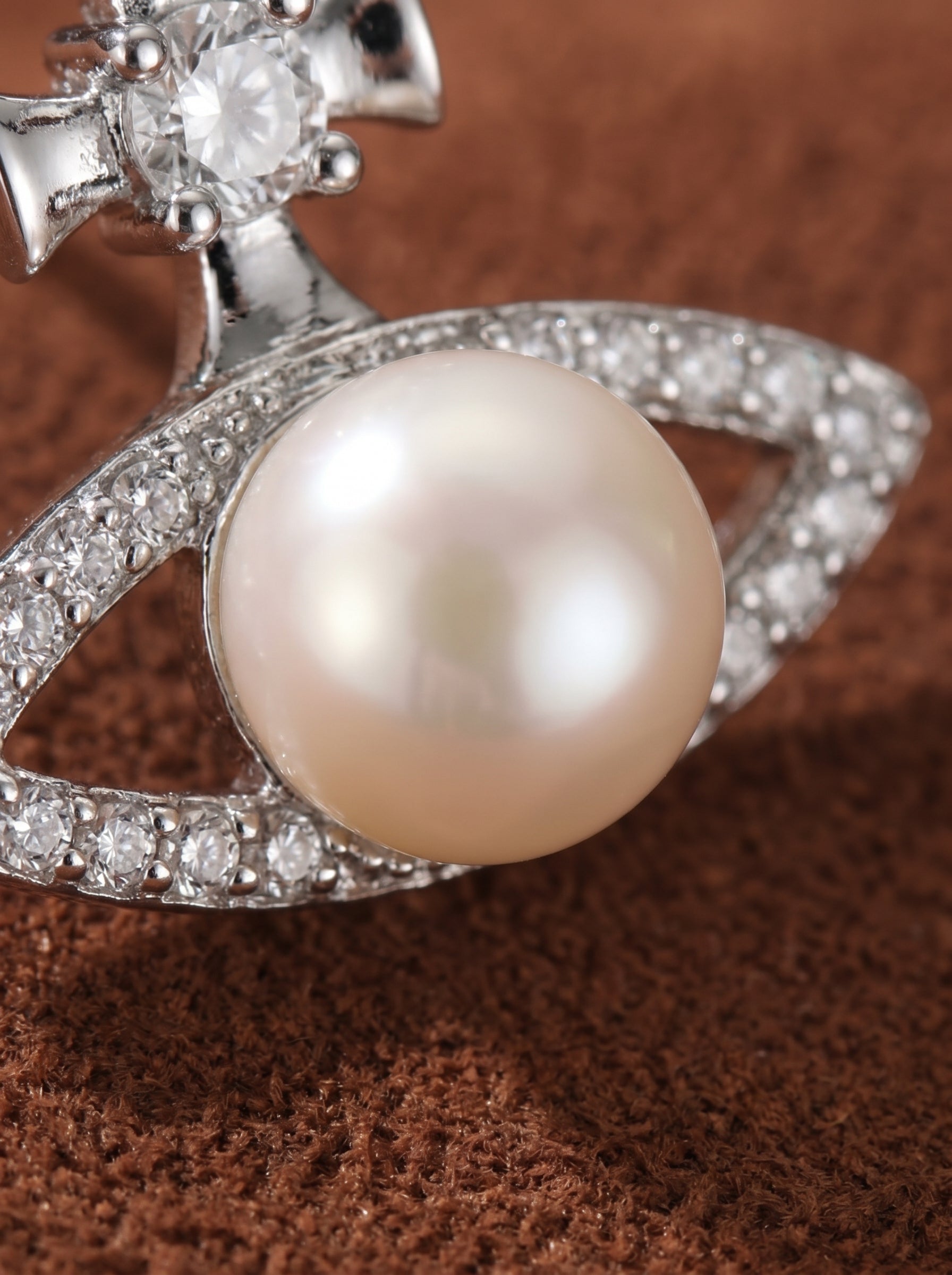 Close-up of a Verity Freshwater Pearl Cross Stud Earring, featuring a lustrous white button pearl set in a sparkling eye-shaped frame adorned with cubic zirconia and a cross motif. @pearl