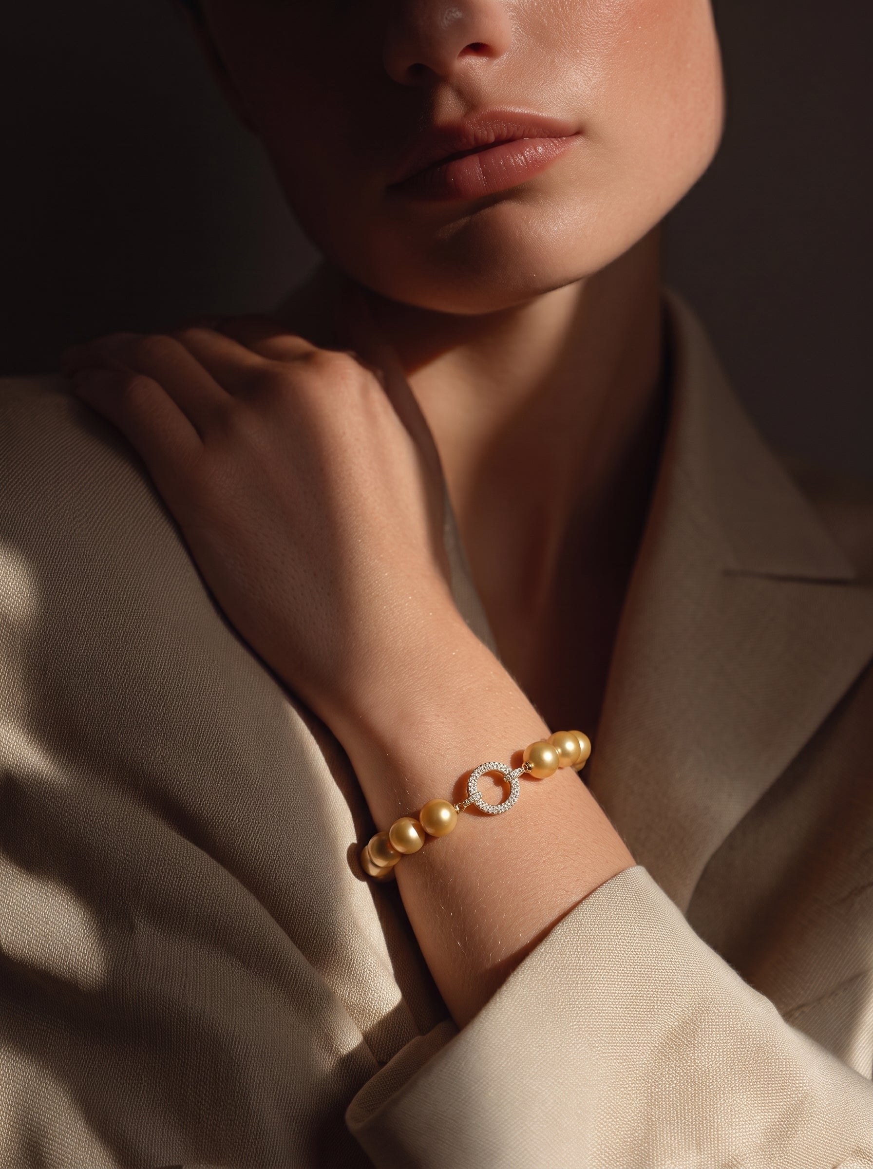 Golden freshwater pearl bracelet with a pavé-set circular clasp on a model's wrist. @model