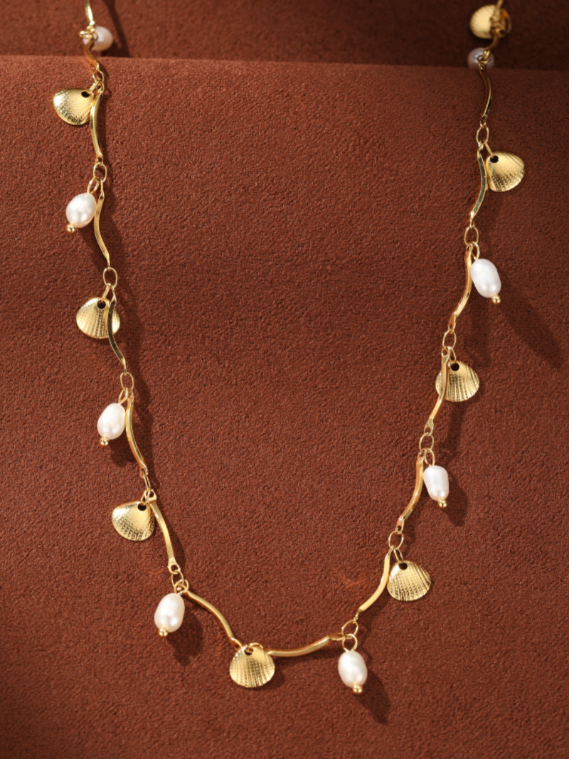 Gold wavy chain necklace with alternating freshwater pearls and seashell charms